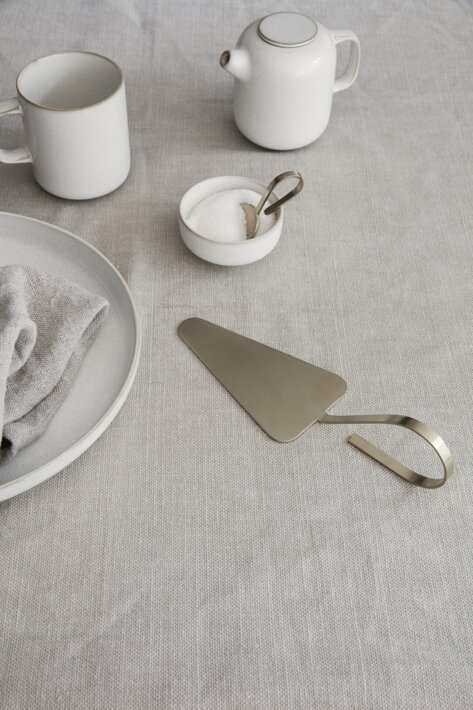 Krémová keramická šálka s uškom na stole s cukorničkou a mliekovkou