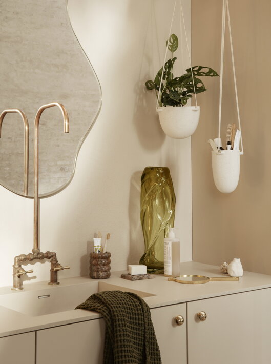Malý nepravidelný kvetináč z bielej kameniny visiaci v kúpeľni ako úložný priestor na kozmetické potreby