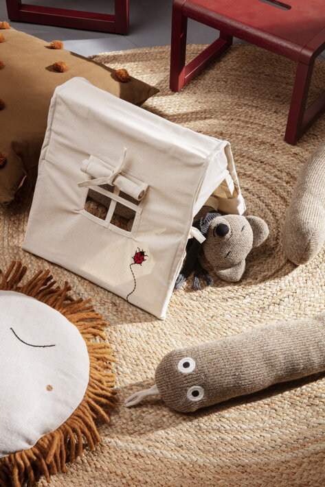 Veľký okrúhly koberec ručne upletený z prírodnej juty v detskej izbe s plyšovými hračkami a miniatúrnym stanom