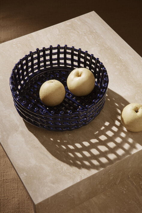 Tmavomodrá ručne tvarovaná misa na ovocie s jablkami na travertínovom konferenčnom stolíku
