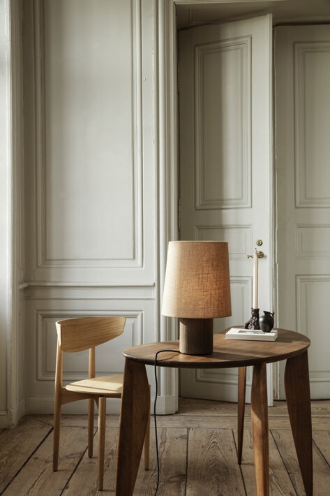 Moderná drevená stolička pri dizajnovom stolíku so stolovou lampou