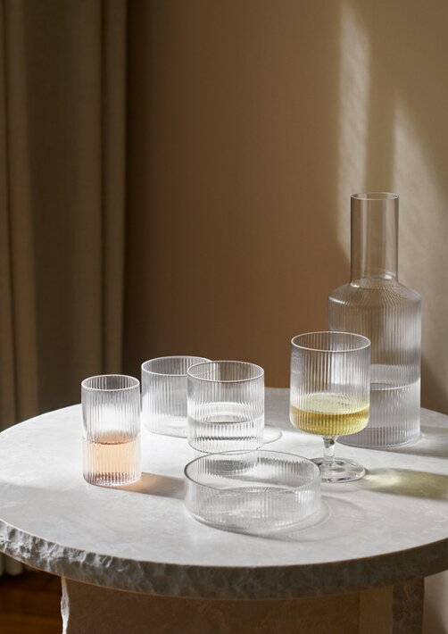 Kolekcia dizajnových pohárov, karafy a misky na mramorovom stole