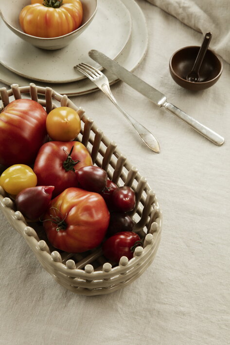 Oválny keramický košík s paprikou a rajčinami na jedálenskom stole