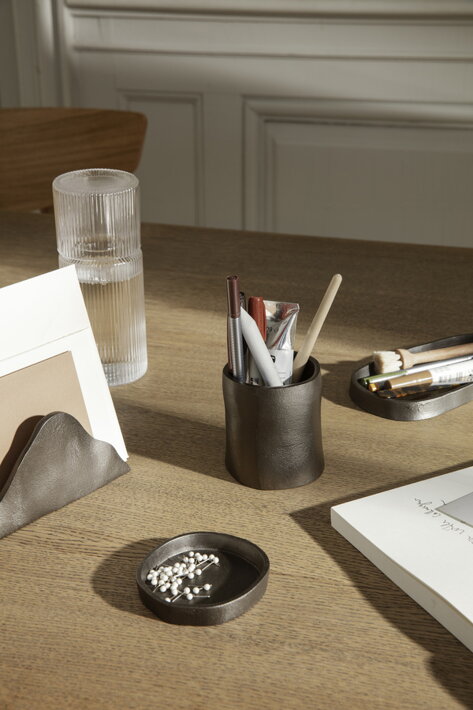 Čierny stojan na dokumenty v organickom dizajne na kancelárskom stole pri dizajnovej karafe