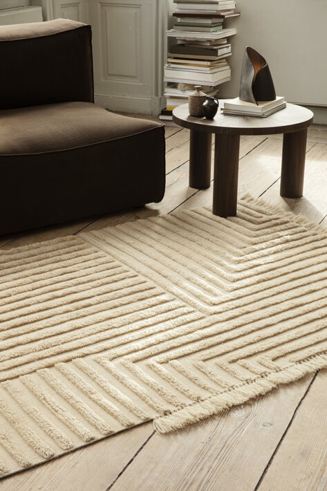 Luxusný vlnený koberec s geometrickým vzorom pri dizajnovej sedačke v obývačke