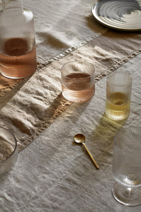 Nízky vrúbkovaný pohár z číreho skla na stole s karafou