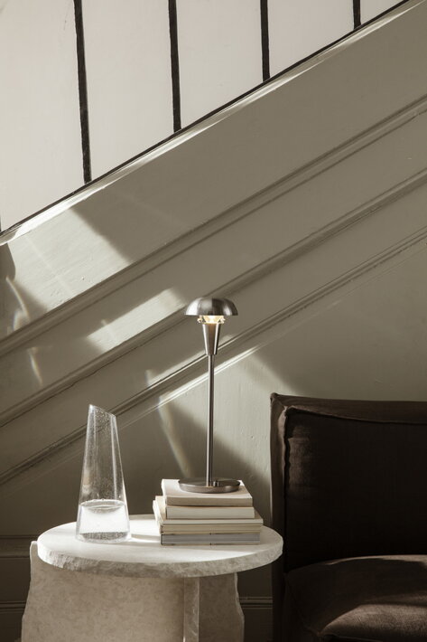 Strieborná stolová lampa s elegantným dizajnom na mramorovom stolíku s karafou