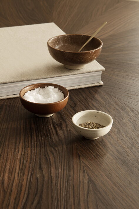 Tri malé misky z porcelánu na soľ, korenie a ochucovadlá na drevenom stole