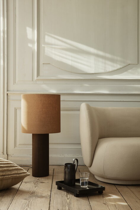 Luxusná stojanová lampa z dreva s okrúhlym tienidlom pri dizajnovej pohovke v obývačke