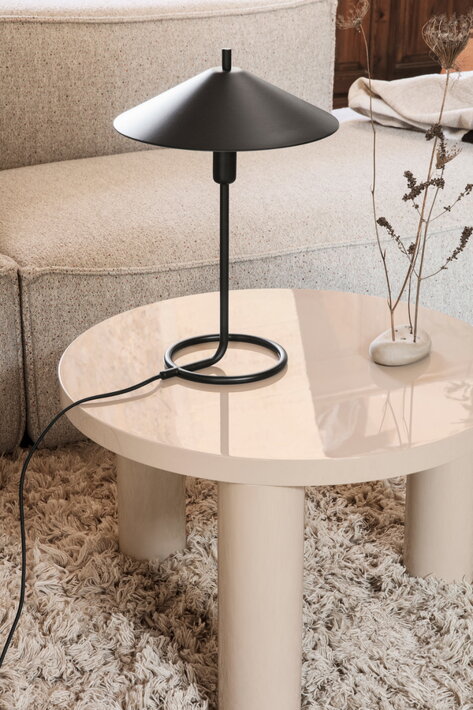 Dizajnová stolová lampa z čierneho kovu na konferenčnom stolíku v obývačke