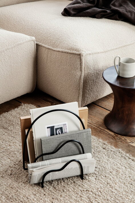 Čierny kovový stojan na noviny a časopisy na koberci v obývačke