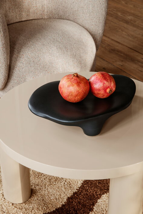 Čierny vyvýšený podnos s jablkami na drevenom stolíku v obývačke