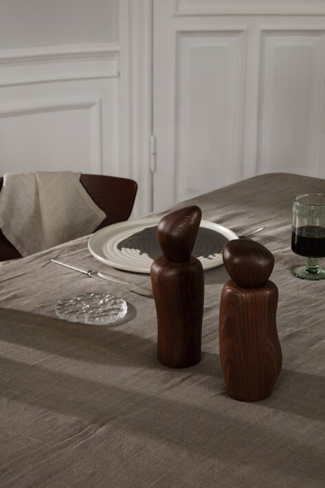 Nepravidelné drevené mlynčeky na korenie a soľ na stole v jedálni