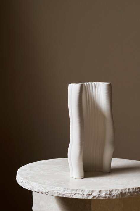 Biela dizajnová váza z vrstvenej kameniny ako samostatná dekorácia na mramorovom stolíku