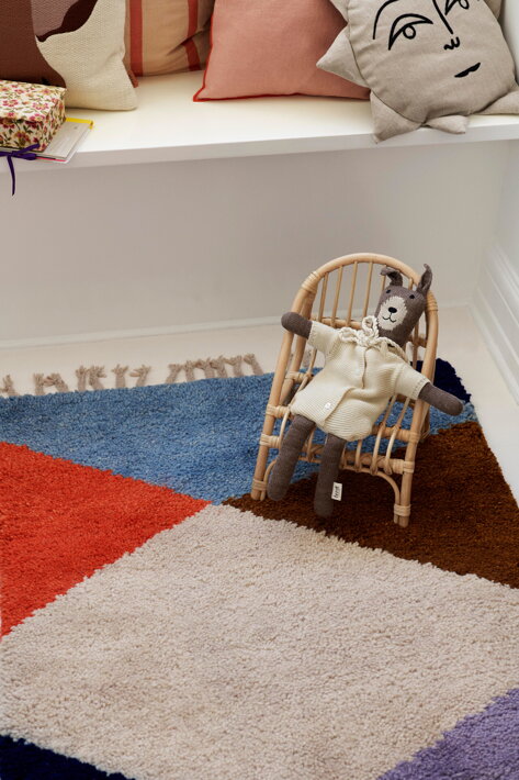 Pletený zajačik  v ratanovom kresle na farebnom koberci v detskej izbe