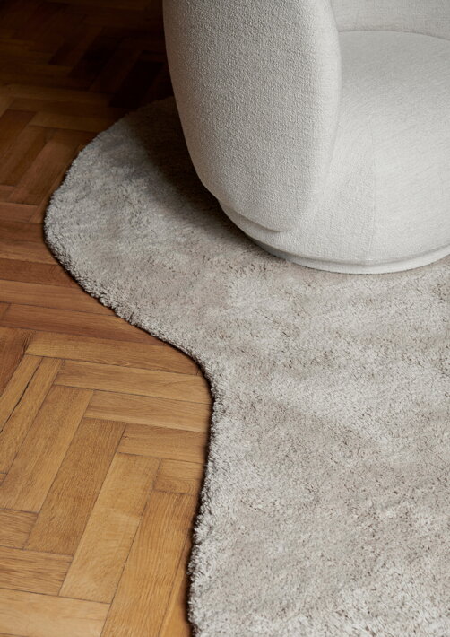Štýlový ručne všívaný koberec z vlny pod dizajnovým kreslom v obývačke