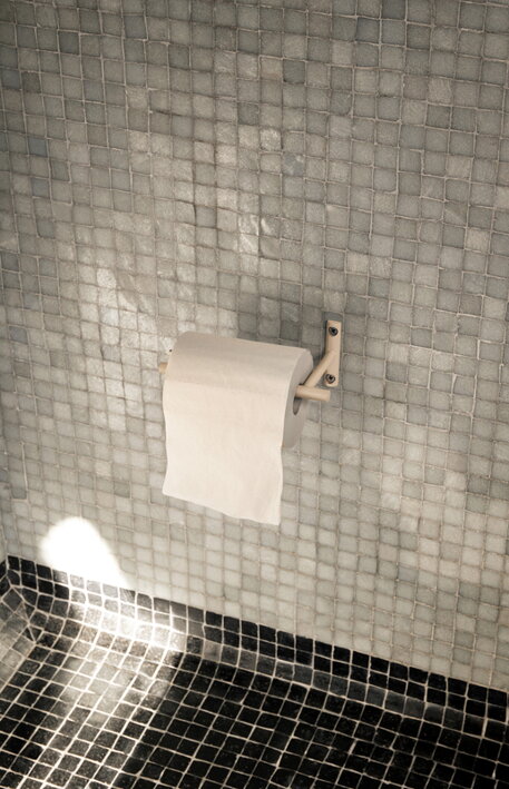 Minimalistický držiak na toaletný papier z kašmírového práškovaného kovu na mozaikovej stene