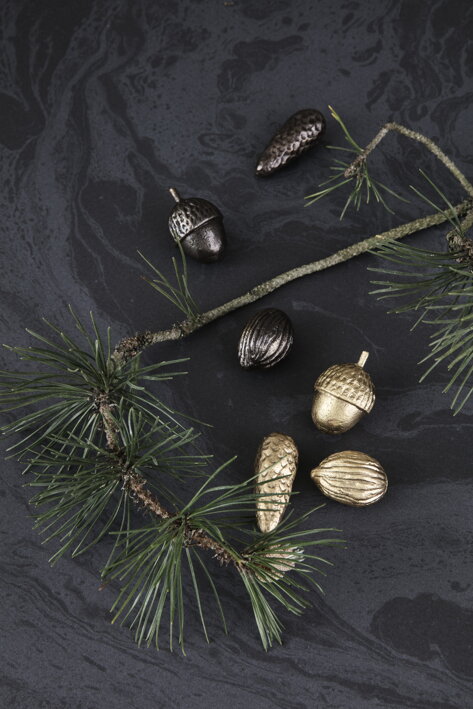 Mosadzná dekorácia plody lesa – šiška, žaľuď a orech na čienom obruse s vetvičkou