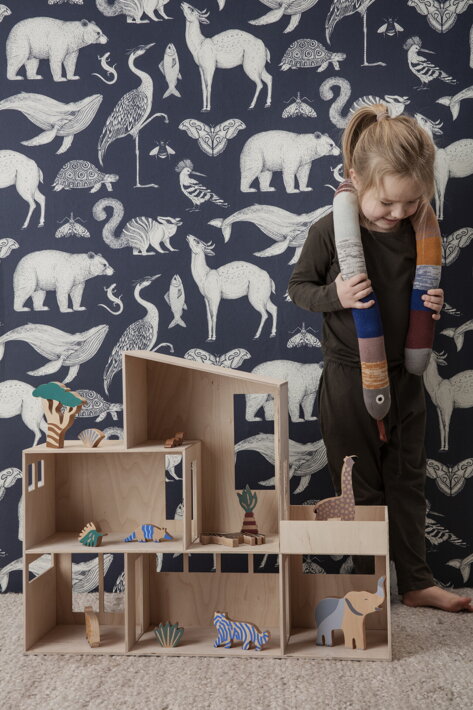Dievčatko stojace pri drevenom domčeku s drevenými zvieratkami