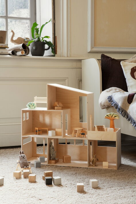 Štýlový drevený domček pre hračky a bábiky na vlnenom koberci v detskej izbe