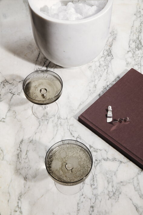 Biela mramorová nádoba s ľadom  na stole pri dymových pohároch so šampanským