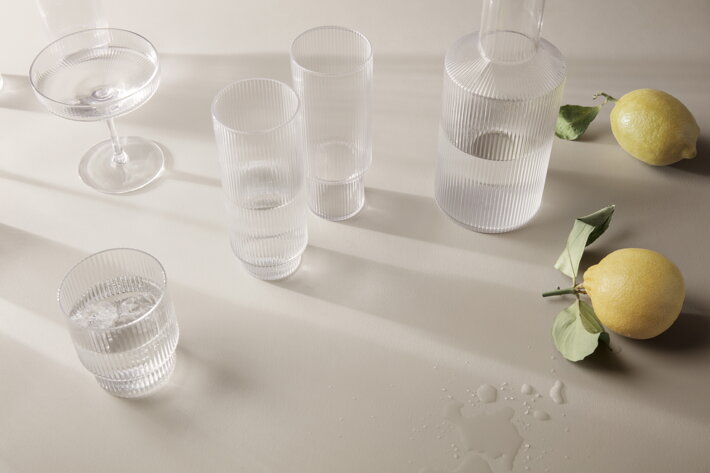 Ručne fúkané číre poháre a karafa s vrúbkovaným dizajnom na stole s citrónmi