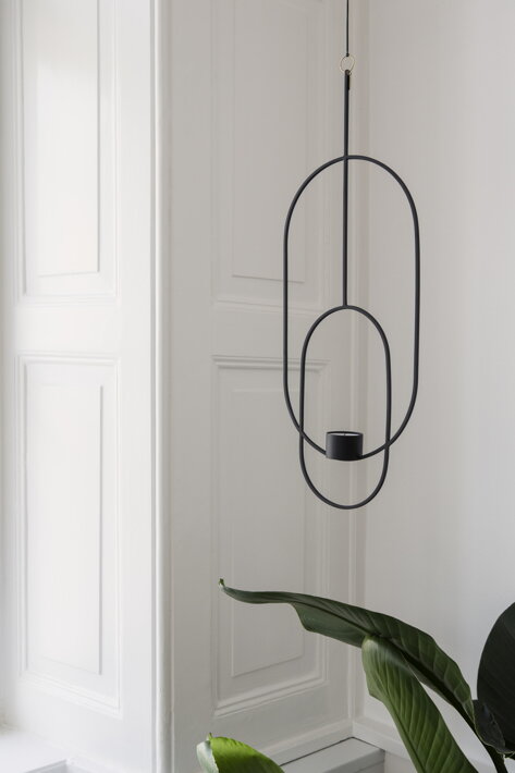 Dizajnový oválny svietnik na čajovú sviečku z čierneho kovu visiaci nad izbovou rastlinou
