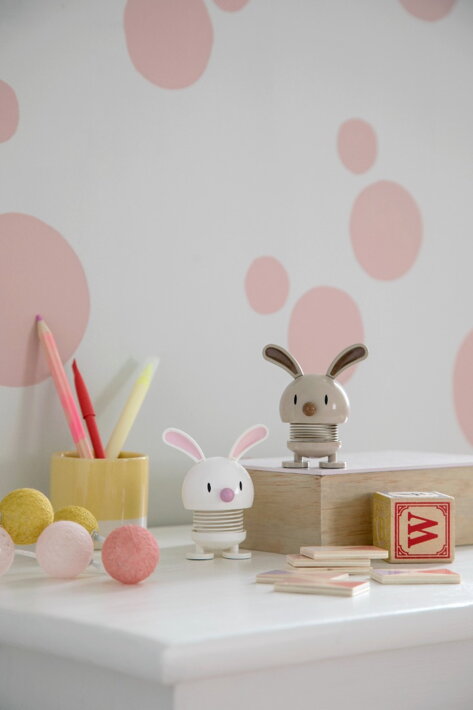 Malá biela dekoračná figúrka s ušami zajac na stole v detskej izbe