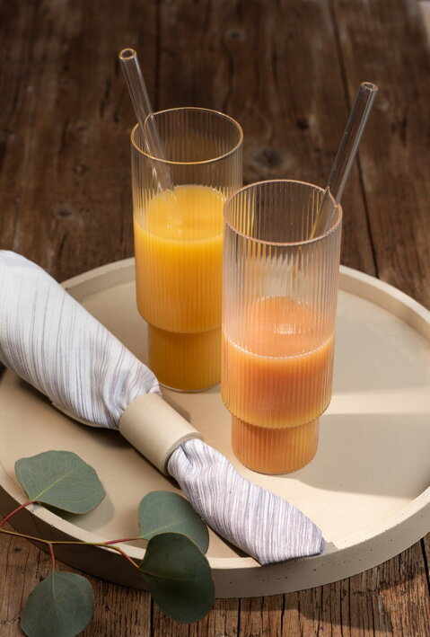 Pomarančový džús vo vysokých pohároch na okrúhlom betónovom podnose