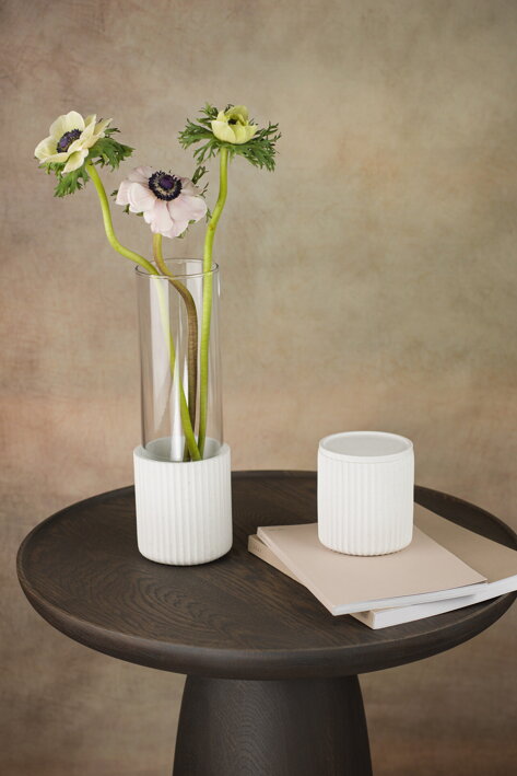 Biela betónová váza s vysokou sklenenou vložkou Waves vedľa betónovej dózy na stole