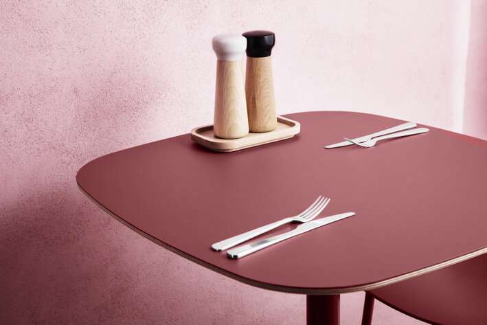Malé drevené mlynčeky na soľ a korenie s mramorovým mlecím mechanizmom na červenom jedálenskom stole