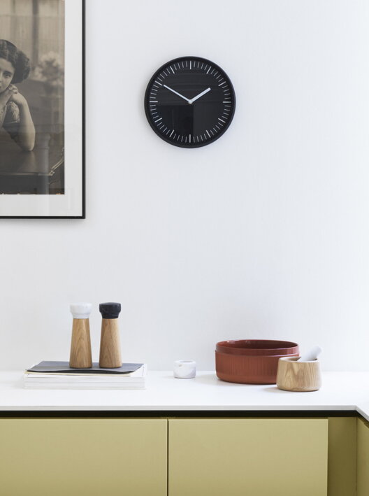 Čierne nástenné hodiny na bielej stene v kuchyni