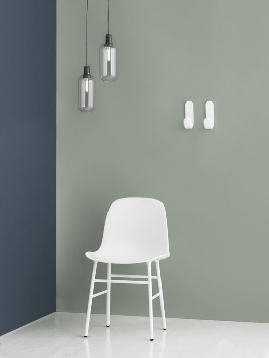 Dva biele drevené háčiky Curve na stene v minimalistickom interiéri
