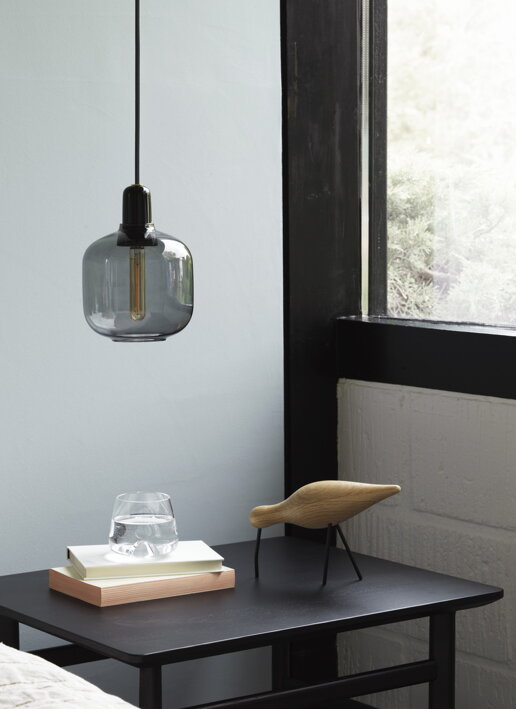 Dizajnový číry pohár s vodou na stole s dreveným vtáčikom v kancelárii