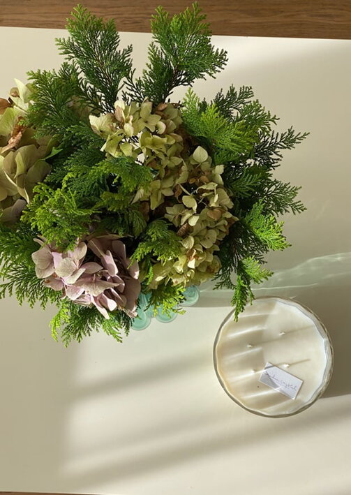 Veľká číra krištáľová sviečka v skle v retro dizajne s vôňou tekvicová víla pri zelenej kytici