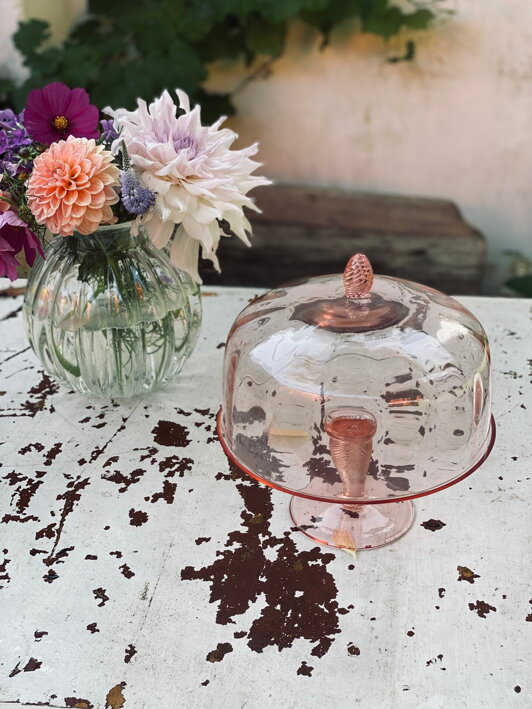 Veľký tortový podnos z ružového krištáľu s ružovým poklopom pri veľkej sklenenej váze