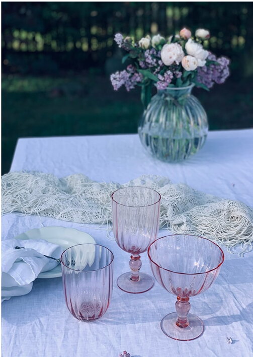 Ružové retro poháre na víno, vodu a sekt na stole s okrúhlou vázou