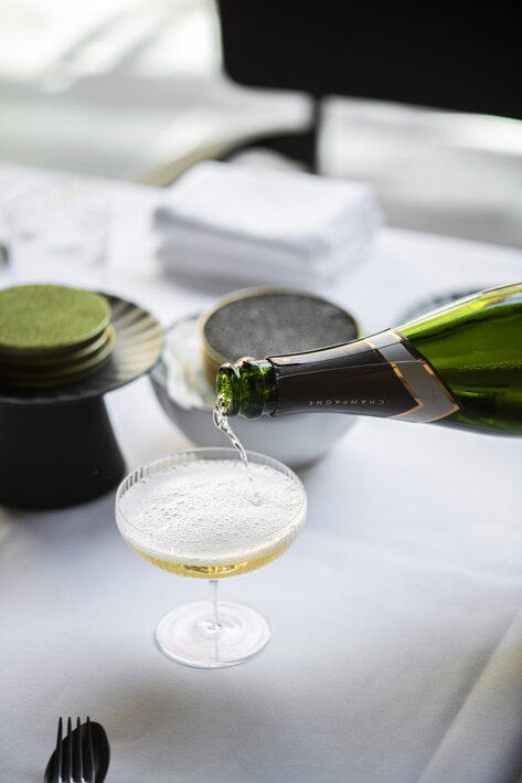 Fľaša Champagne nad ručne fúkaným vrúbkovaným pohárom so šampanským