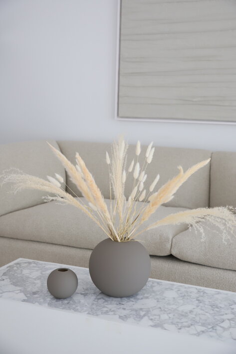 Biele sušené kvety v bielej keramickej váze v obývačke