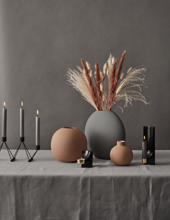 Čierna mramorová kocka s mosadzným svietnikom na čajovú sviečku na stole s vázami