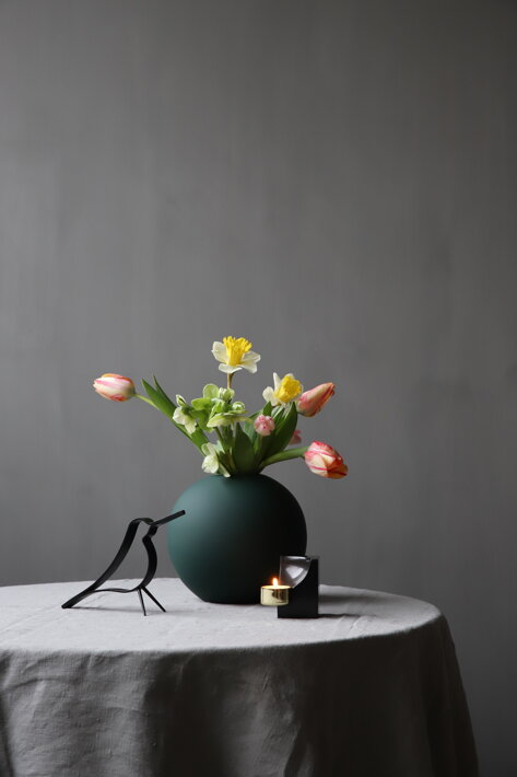 Čierny mramorový svietnik na čajovú sviečku na stole s vázou a dekoračným vtáčikom