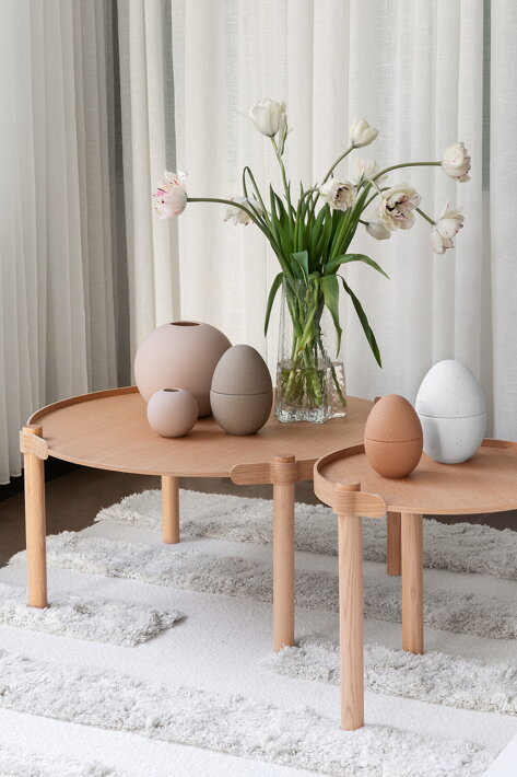 Elegantné keramické dekorácie v tvare vajíčka na stole s kyticou kvetov