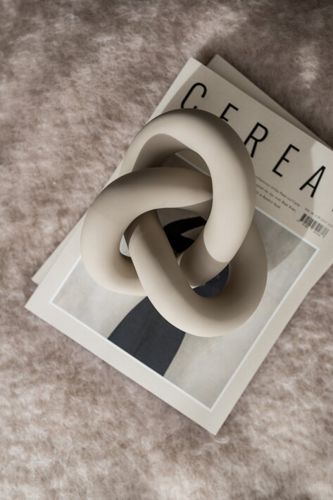 Piesková keramická dekorácia v tvare veľkého nekonečného uzla na magazíne o dizajne