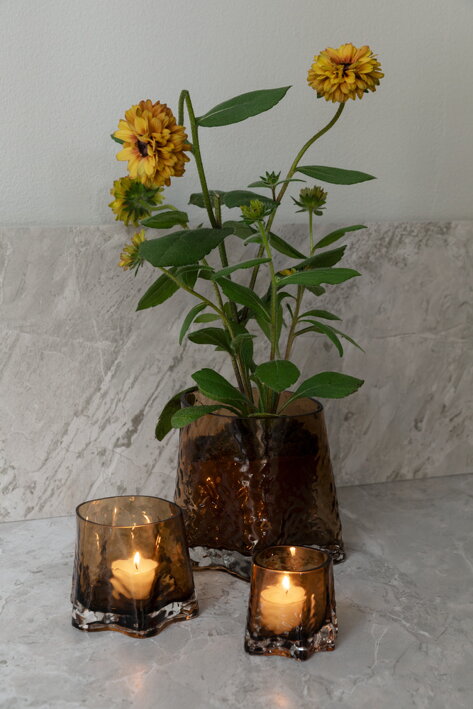 Sklenený hnedý svietnik na čajovú sviečku pri štýlovej váze s kvetmi