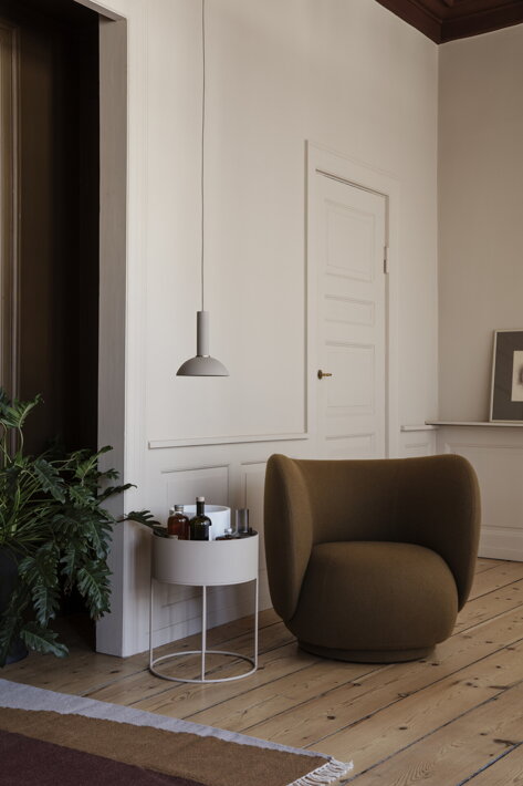 Vyvýšený príručný stolík s úložným priestorom v kašmírovej farbe pri dizajnovom kresle v obývačke