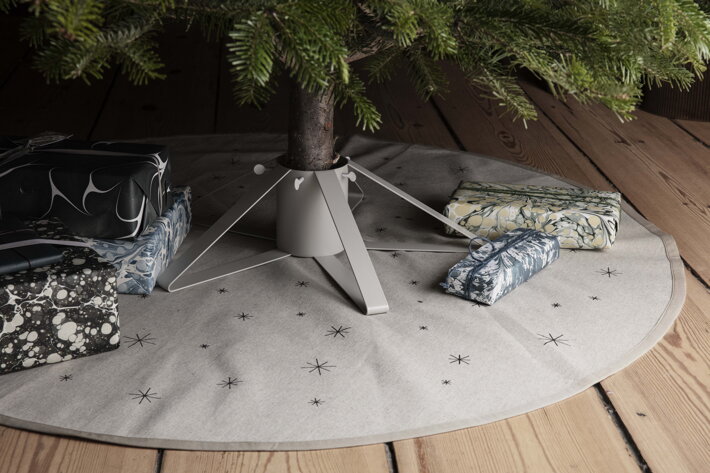 Piesková okrúhla podložka na drevenej podlahe pod vianočným stromčekom