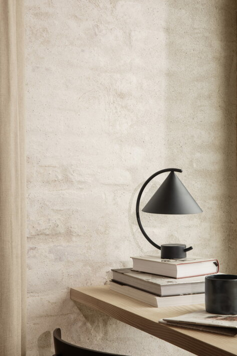 Dizajnová bezdrôtová lampa z čierneho kovu v kútiku na čítanie