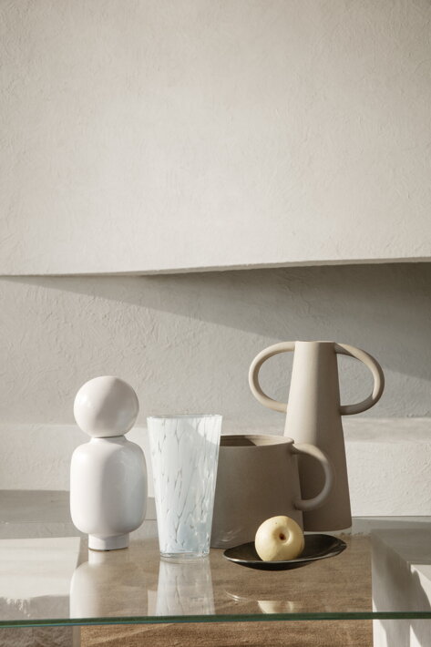 Dekoračné hlinené nádoby na stole s dizajnovou vázou a pohárom