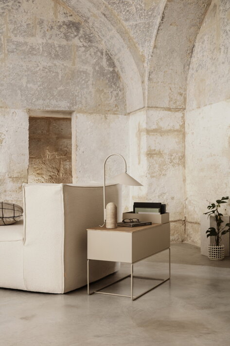 Minimalistická dizajnová lampa na príručnom stolíku pri dizajnovej sedačke v obývačke