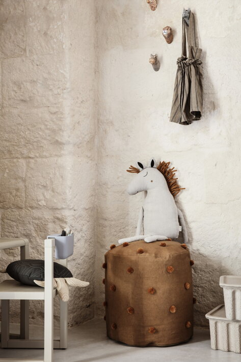 Veselý detský puf so všívanými bodkami v rohu detskej izby s plyšovým koníkom
